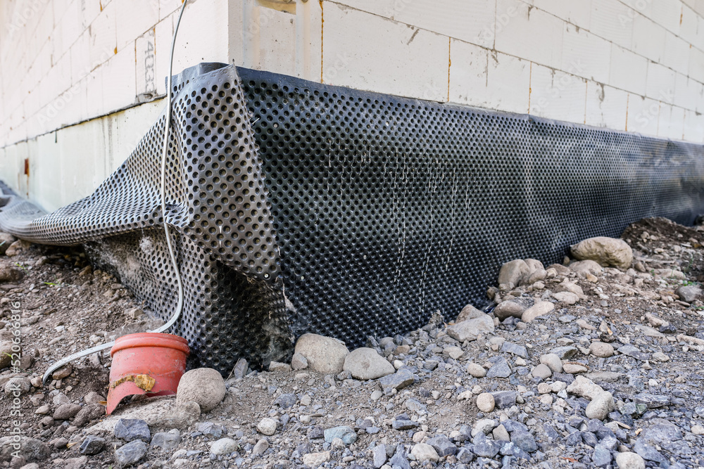 Black dimpled house foundation drain waterproofing membrane installed