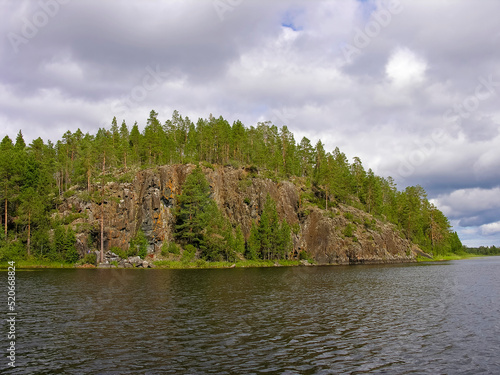 High rocky bank of the lake overgrown with pine forest. photo