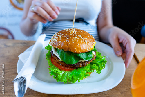Veggie burger healthy vegan food. Salad  avocado  vegetable on vegetarian hamburger eating cute woman. Vegan sandwich healthy diet food.
