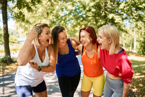 Laughing group of female friends having fun during outdoor exercise in park