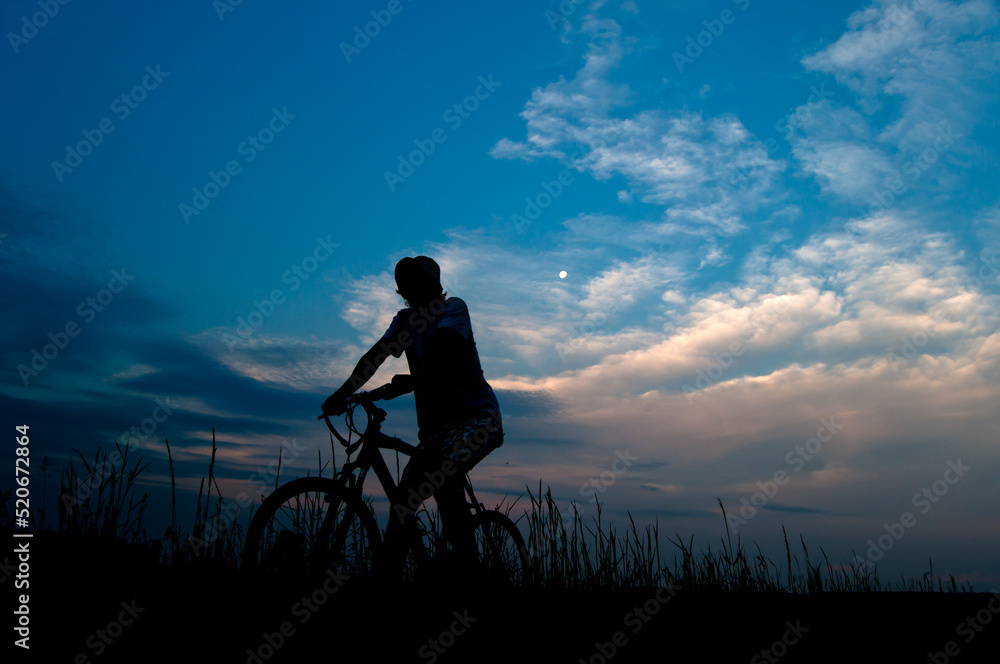 Silhouette of man on the bicycle in the nature at summer night Silhouette of man on the bicycle in the nature at summer night