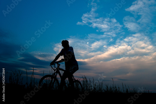 Silhouette of man on the bicycle in the nature at summer night 