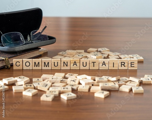 communautaire mot ou concept représenté par des carreaux de lettres en bois sur une table en bois avec des lunettes et un livre