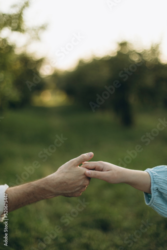 a man and a woman hold hands in the evening against the backdrop of the greenery of nature. male and female hand together © Anne Ponomarenko