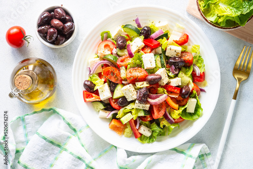 Greek salad with olives, feta cheese and fresh vegetables on white.