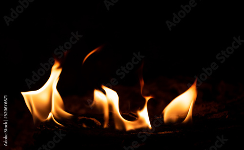 Flame in the fireplace, yellow tongues of fire. Black background. Firewood burning. Heating the house with a fireplace.