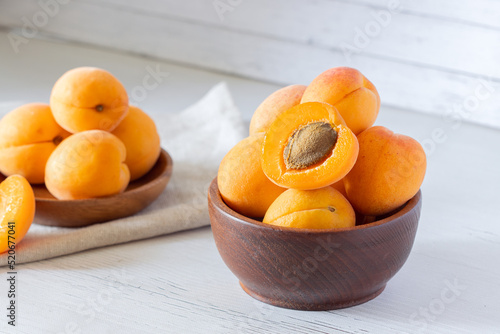 apricots in a wooden bowl on a light wooden background, apricot cut in half, fresh fruit