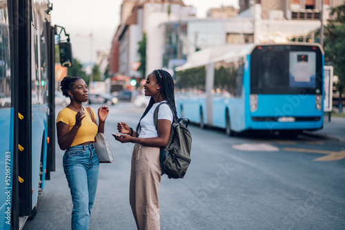 Two african american woman waiting for a bus