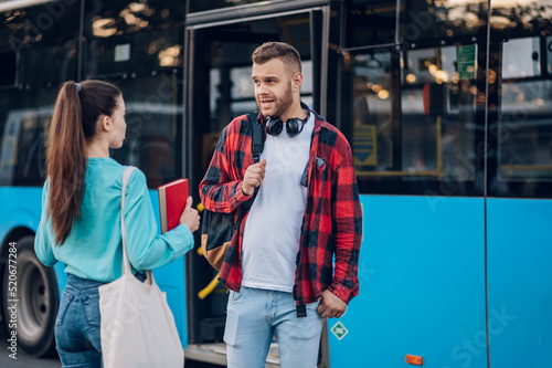 Two friends waiting for a public transport at a bus stop