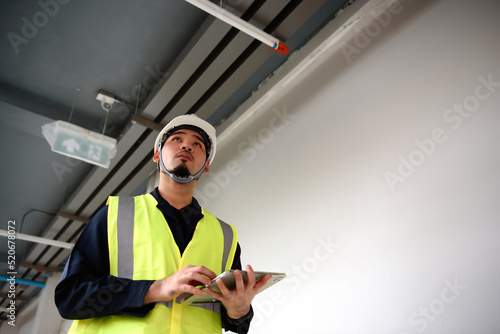 Young engineer apprentice working with technology tablet in survey and check the detail of building in the construction site for manage in the job