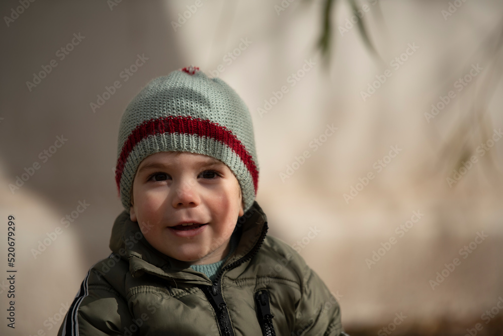 Niño bebé con gorro de lana sonriendo y mirando a la cámara Niño bebé con gorro de lana sonriendo y mirando a la cámara
