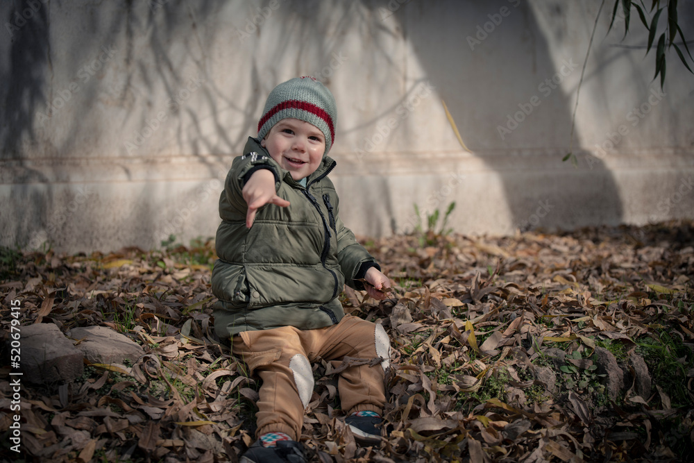 Niño bebé jugando con las hojas caídas de los árboles en otoño invierno