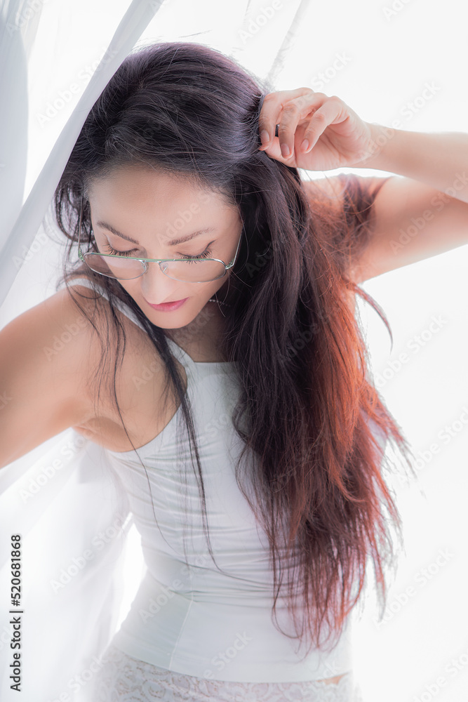 Beautiful latina woman in white lingerie standing next to a window, she is very happy posing Beautiful latina woman in white lingerie standing next to a window, she is very happy posing