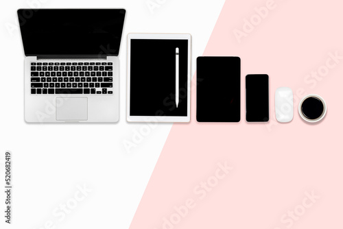 Flat lay photo of Office table with laptop computer, digital tablet, and mobile phone on modern two tone background.
