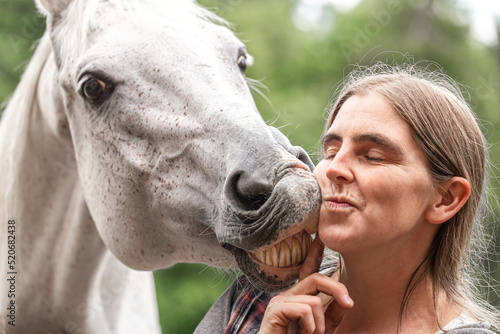 Funny equestrian team scene: A horse showing a kissing trick on command. Horse and owner having fun and joy