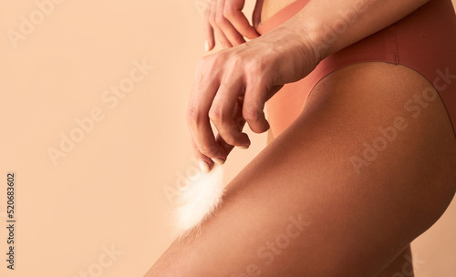 Canvas Print Close-up image of a woman holding a feather on her legSmooth skin, depilation