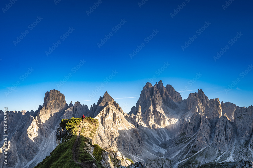 Fototapeta premium Junger Mann rennt auf atemberaubenden Aussichtspunkt in den Dolomiten