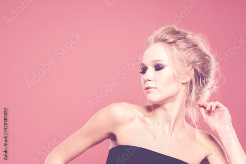 Dancing girl with bare shoulders in the studio on a pink background.