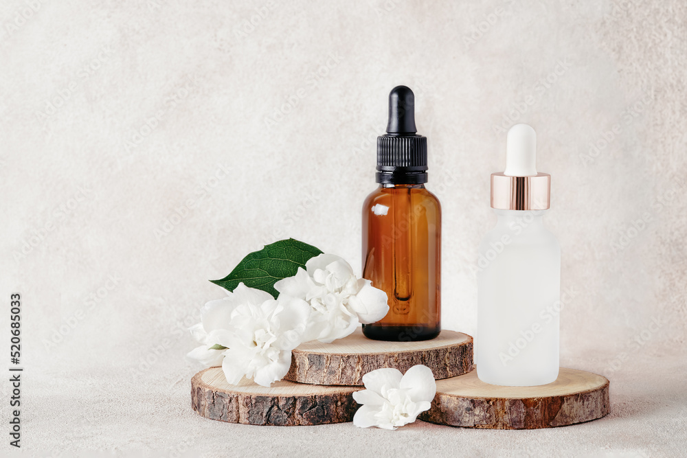 Glass dropper bottles for medical and cosmetic use and jasmine flowers on wooden cut. SPA concept. Glass dropper bottles for medical and cosmetic use and jasmine flowers on wooden cut. SPA concept.