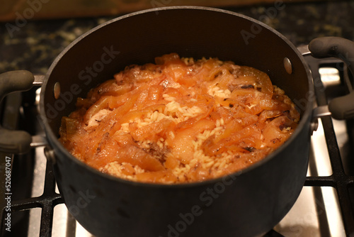 close up of rice and onions cooking in a black pot.