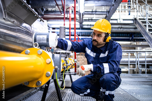 Tableau sur toile Refinery blue collar worker standing by LPG pipeline and checking gas production or distribution