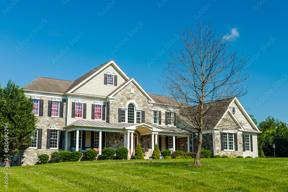 Obraz premium Front view of a large country house. Large freshly cut lawn and trees in the foreground.