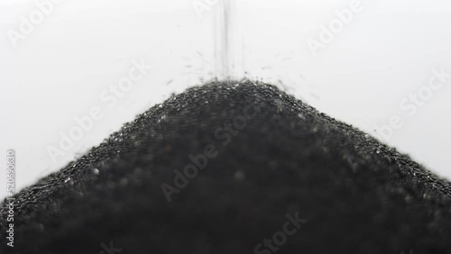 Grains of black sand and quartz are falling in a glass hourglass. photo