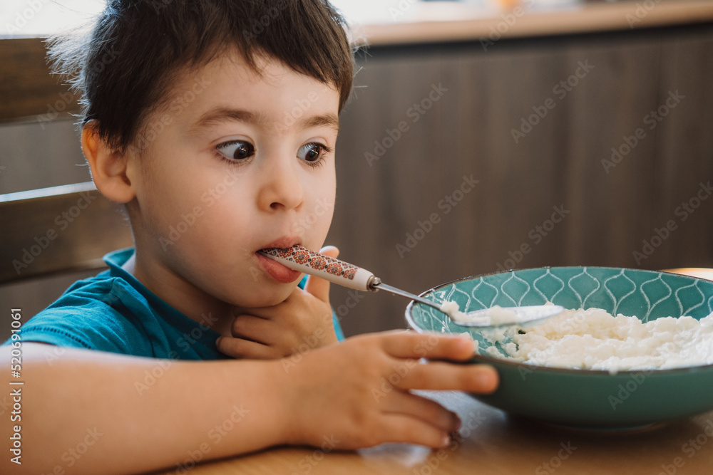 Boy who has finished eating porridge, and caress, holding the spoon in his mouth. Beautiful portrait. Healthy meal. Healthy breakfast. Positive person. Boy who has finished eating porridge, and caress, holding the spoon in his mouth. Beautiful portrait. Healthy meal. Healthy breakfast. Positive person.