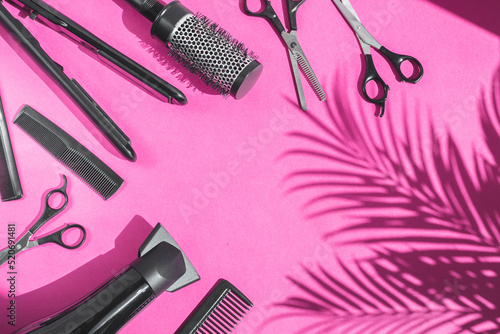 Scissors, combs, hairdryer and hair straightener on a lilac background.