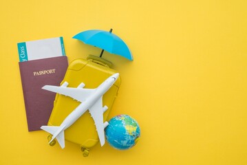 Red umbrella cover airplane, passport, flight tickets and suitcases travelers on yellow background. Travel insurance covers loss suitcase, flight delays, cancellations, accident and medical expenses.