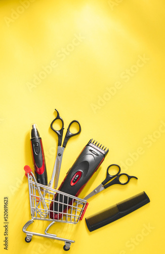 Scissors, combs and hair and ear clippers, nose clippers in a mini cart on a yellow. photo