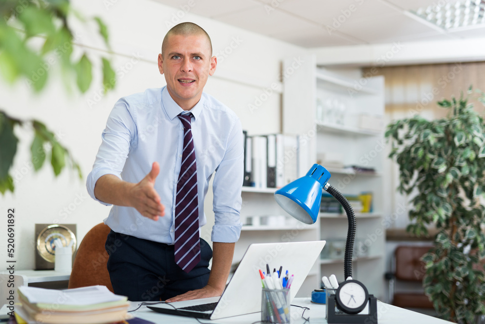 Fototapeta premium Portrait of positive businessman meeting partners at company office, giving hand