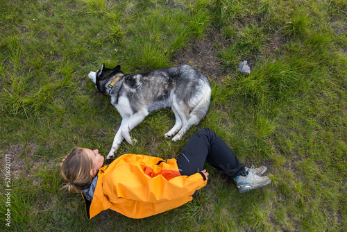 Tourist girl lying with her friend Siberian husky dog hiking in the green mountains