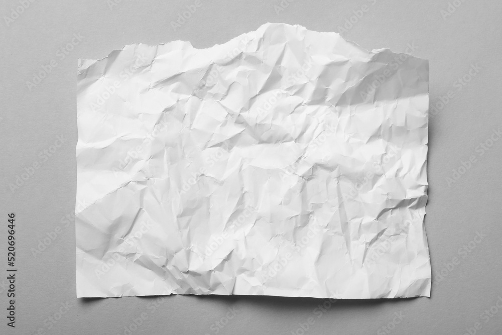 Sheet of white crumpled paper on grey background, top view Sheet of white crumpled paper on grey background, top view