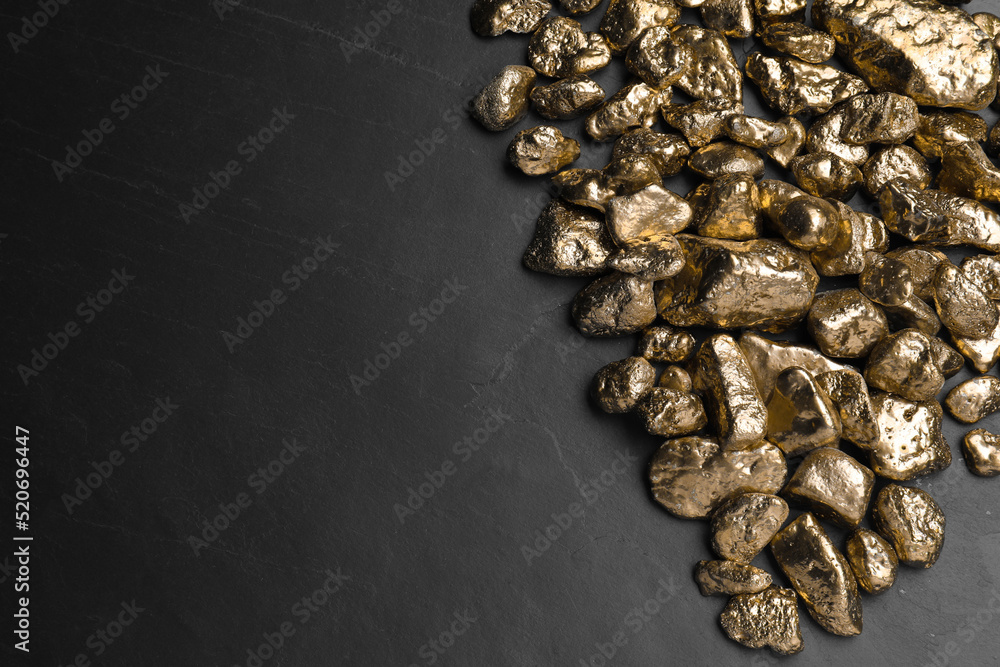 Pile of gold nuggets on black table, flat lay. Space for text Pile of gold nuggets on black table, flat lay. Space for text