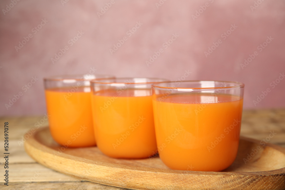 Glasses of freshly made carrot juice on wooden plate Glasses of freshly made carrot juice on wooden plate