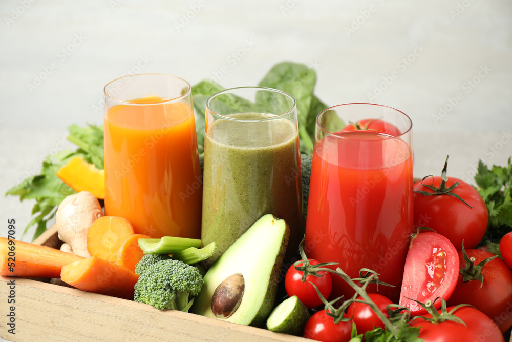 Delicious vegetable juices and fresh ingredients on light background Delicious vegetable juices and fresh ingredients on light background