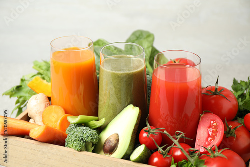 Delicious vegetable juices and fresh ingredients on light background