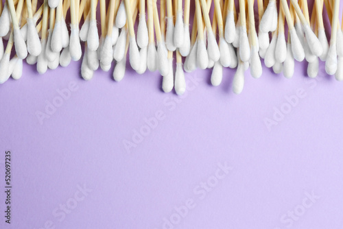 Many cotton buds on violet background  flat lay. Space for text