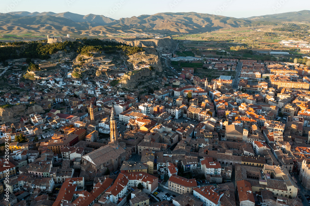 Picturesque drone view of Calatayud cityscape in spring in valley of Iberian mountain area overlooking brownish tiled roofs of residential buildings, Spain