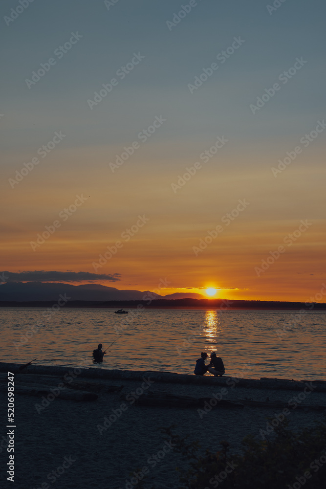 beach sunset at Carkeek Park, Seattle with couple, man fishing, boat