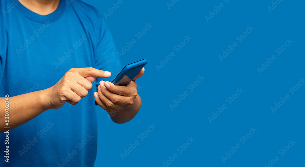 Close-up of hands man in a blue casual using a mobile phone while standing on a blue background