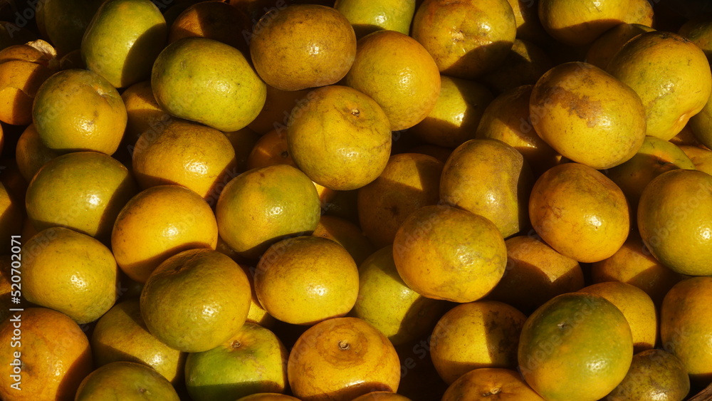 Pile of yellow oranges exposed to sunlight. Focus selected