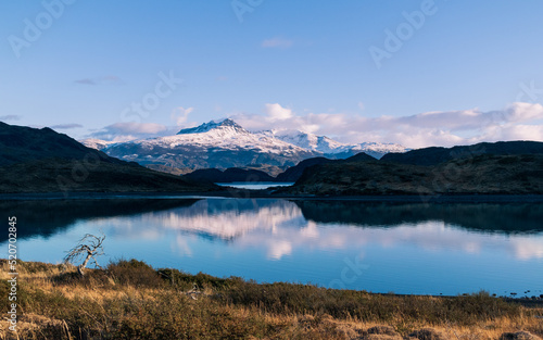 orilla de lago azul con nubes y cerros reflejados, montaña nevada y cielo azul con nubes en las montañas 