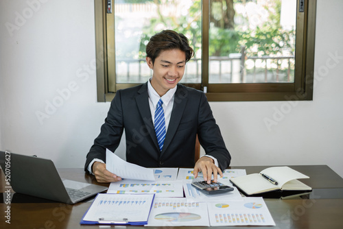 Young Asian businessman financial market analyst sits at their desks and calculate financial graphs showing the results of their investments planning the process of successful business growth