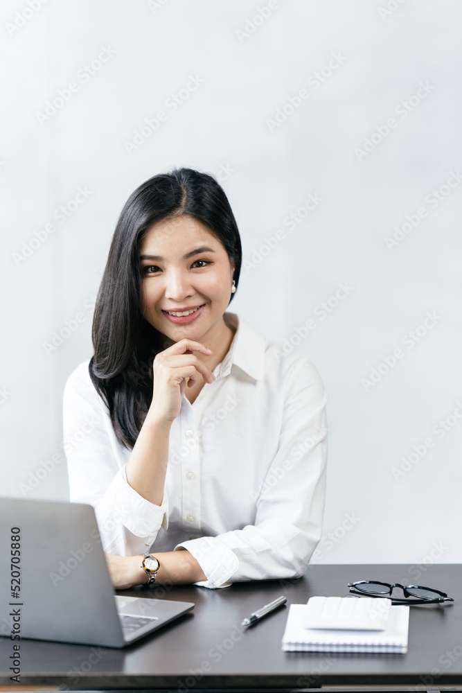Asian business woman using laptop while sitting at home, smiling businesswoman working from home. Asian business woman using laptop while sitting at home, smiling businesswoman working from home.