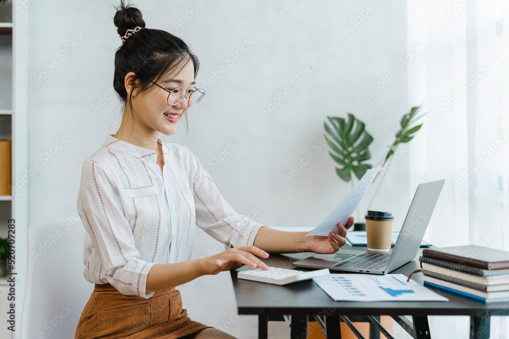 Portrait of a pretty cute asian woman using calculator to do math ...