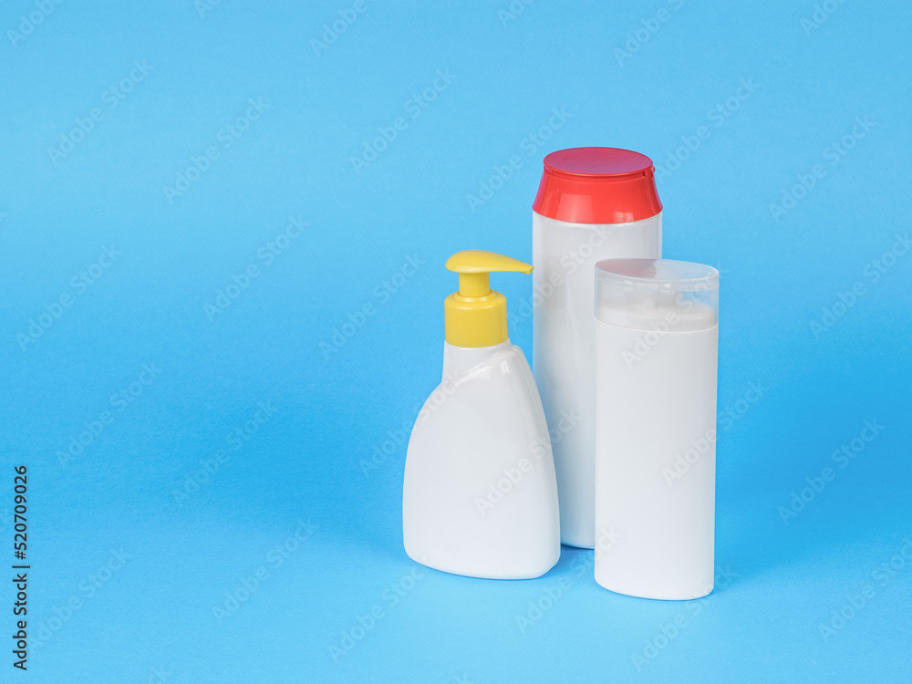 Three white bottles of cleaning products on a blue background. Three white bottles of cleaning products on a blue background.