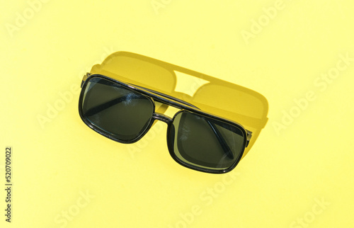 Sunglasses in bright light on a yellow background.