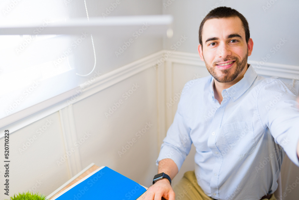 Attractive man smiling at his desk while working from home Attractive man smiling at his desk while working from home